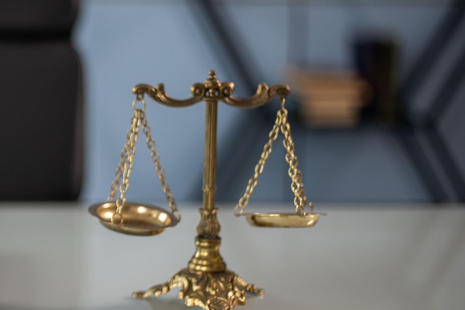Balanza de la justicia sobre un escritorio, con un fondo de oficina desenfocado.