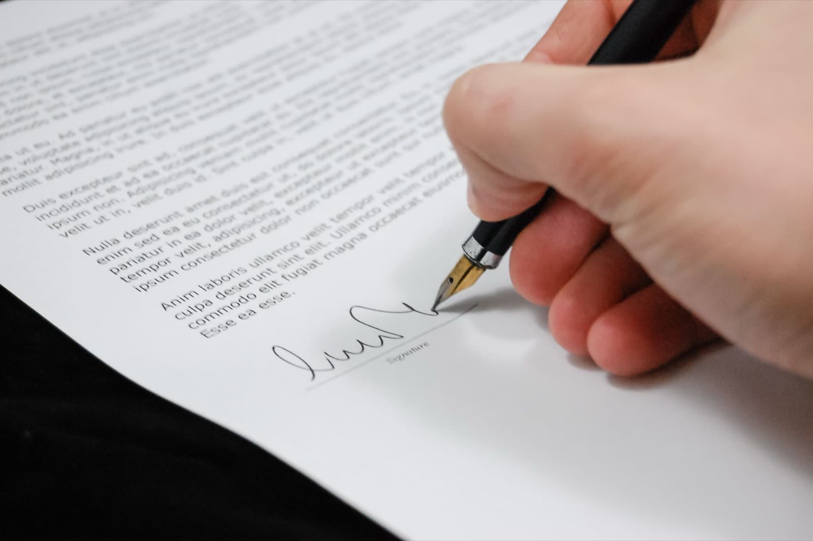 Mano firmando un documento con una lapicera pluma