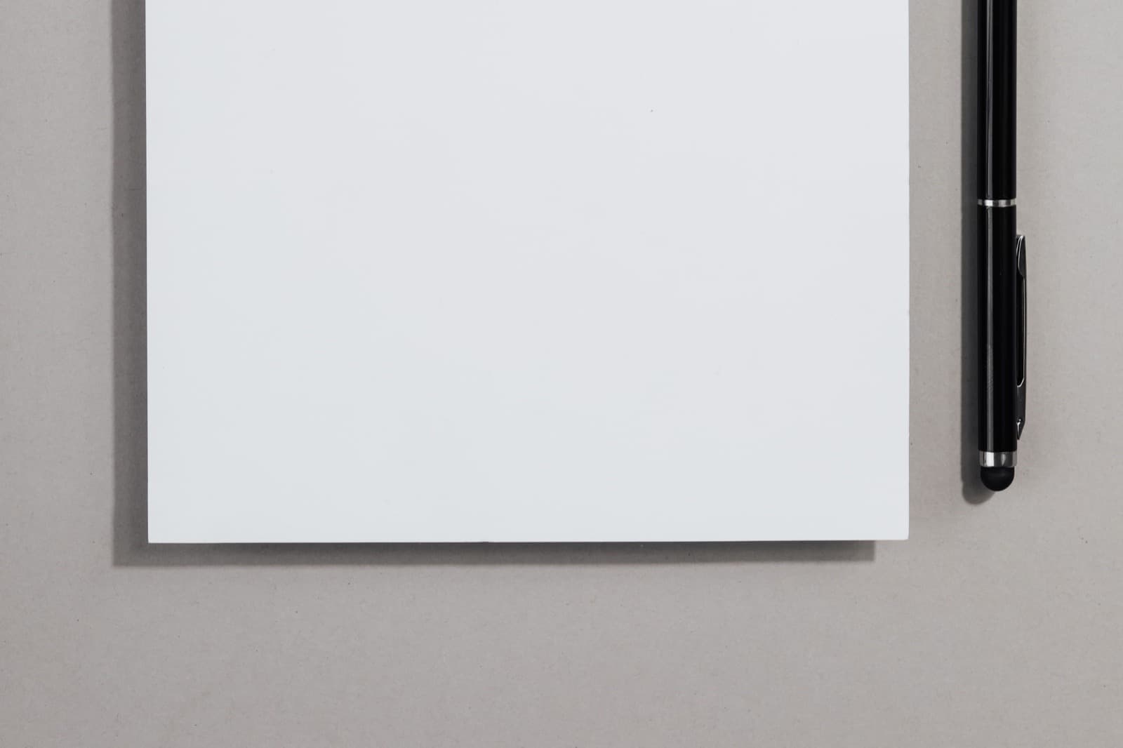 Hoja de papel en blanco y una lapicera sobre una superficie clara.